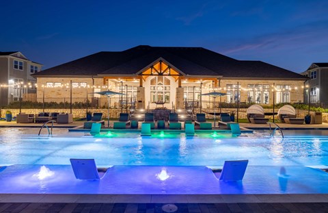 a swimming pool at night with a building in the background