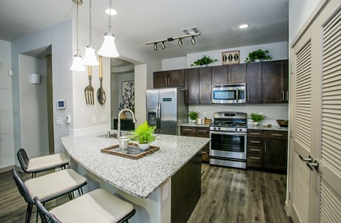 A modern kitchen with a granite countertop and stainless steel appliances.