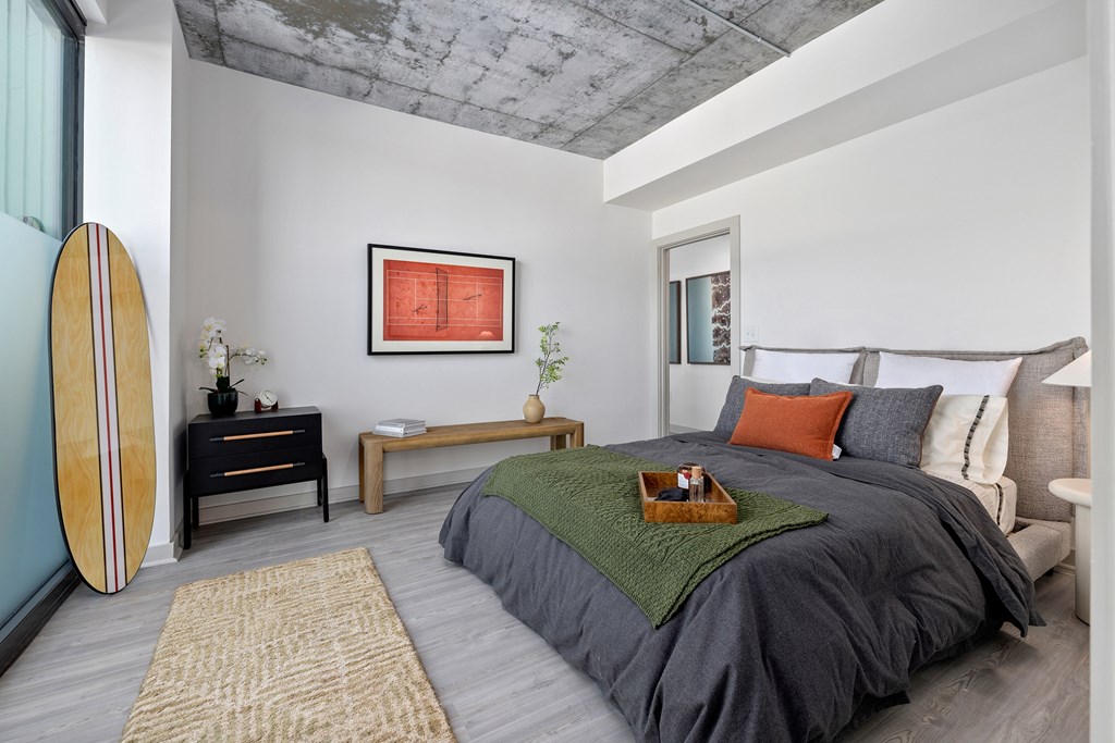 A bedroom with a surfboard leaning against the wall.