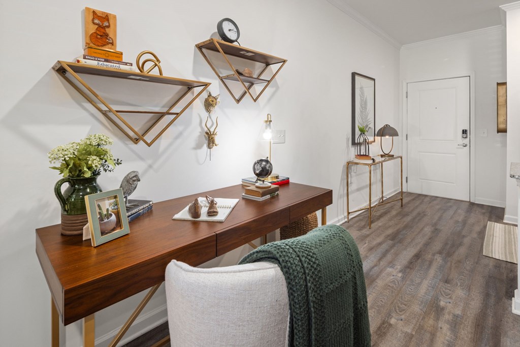 A room with a desk and a chair with a green blanket draped over the back of the chair.