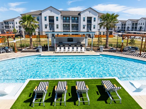A pool with chairs and a building in the background.