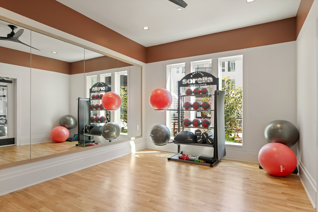 A room with a mirrored wall and a shelf with exercise equipment.
