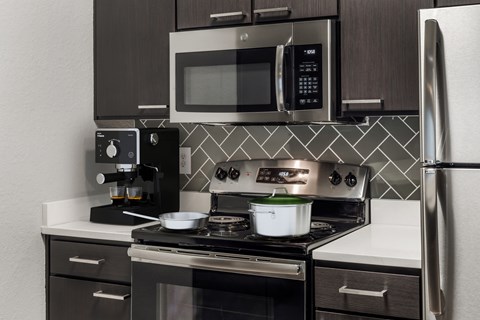 A modern kitchen with a stove, microwave, and refrigerator.