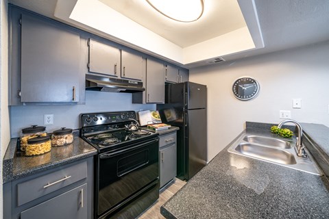 A kitchen with a black stove top oven and a black refrigerator.