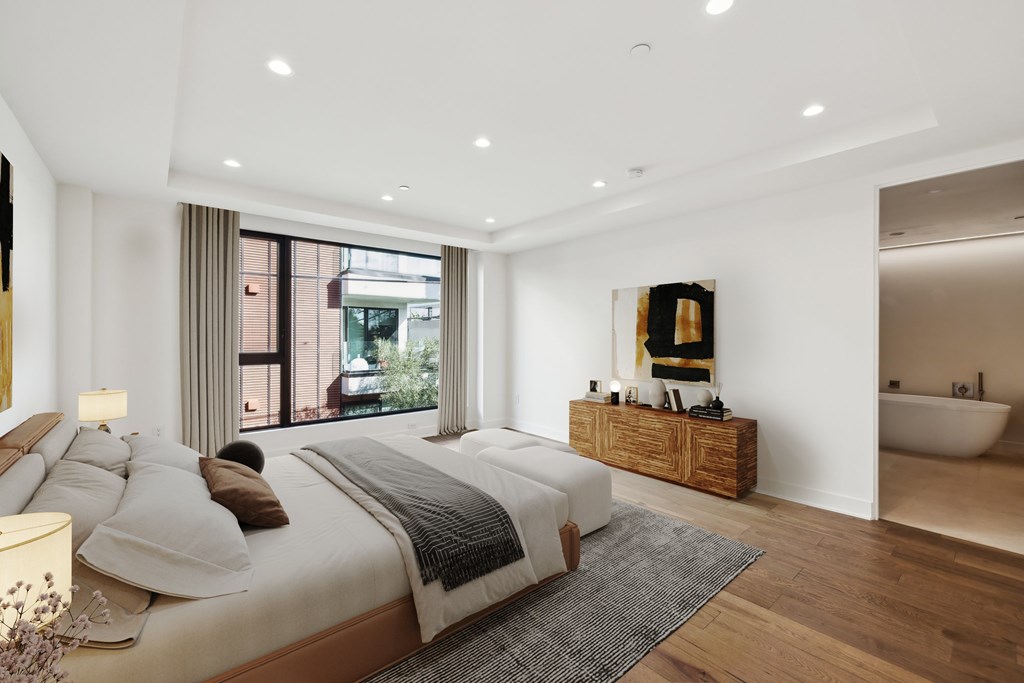 A bedroom with a large bed and a soaking bathtub.