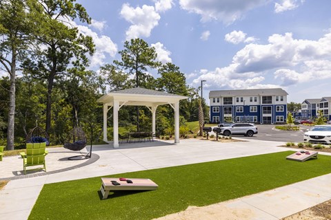 A gazebo is surrounded by a grassy area and trees.
