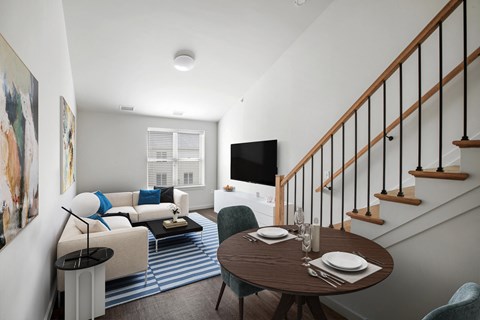 a living room with a staircase in the background and a dining table and chairs in the foreground