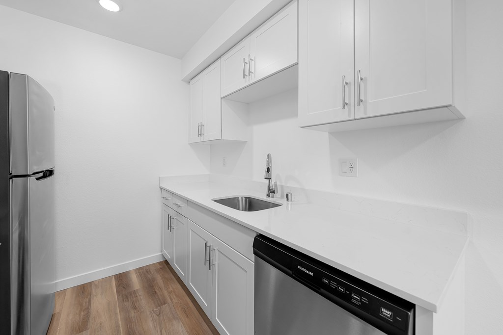 A modern kitchen with a stainless steel dishwasher and white cabinets.