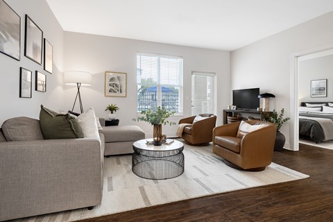 A living room with a grey couch, a brown armchair, and a small table with a plant on it.