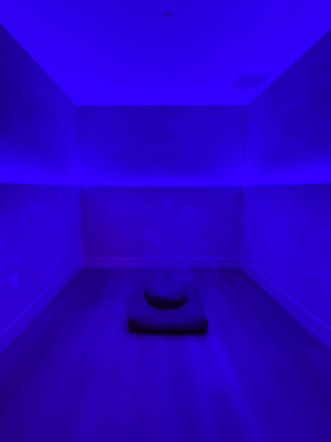 A room with a blue light and a chair in the middle.