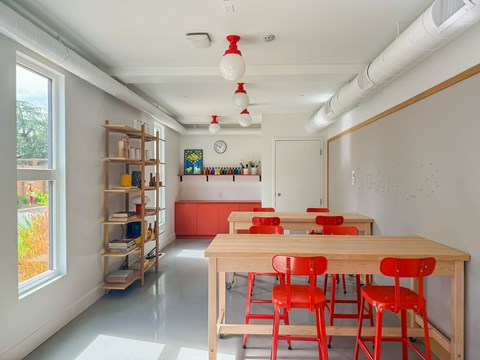 A room with a long table and red chairs.