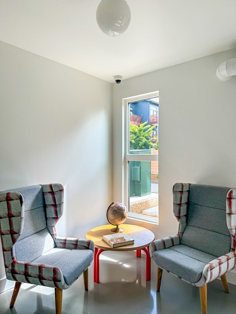 Two chairs and a table are in a room with a window.