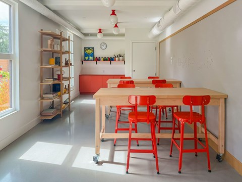 A room with a long table and red chairs.