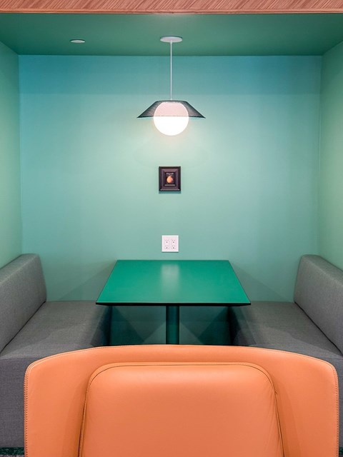 A room with a green table and orange chair.