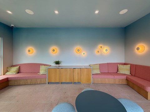 A room with a pink couch, a wooden cabinet, and a blue chair.