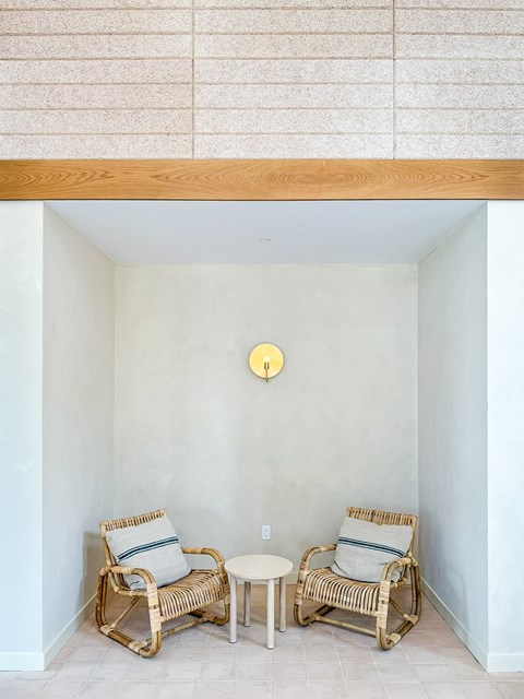 Two wicker chairs and a small table are placed in a corner of a room.