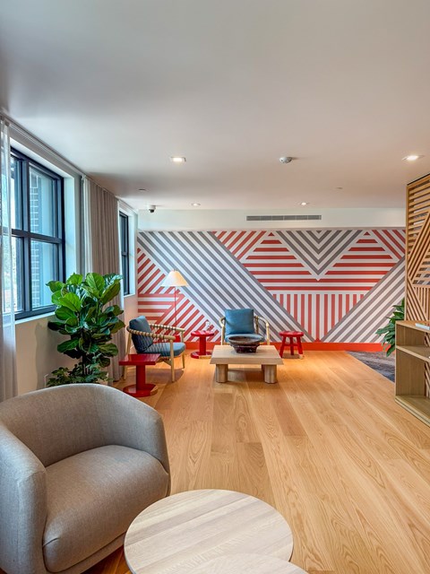 A living room with a grey sofa, a wooden coffee table, and a striped wallpaper.