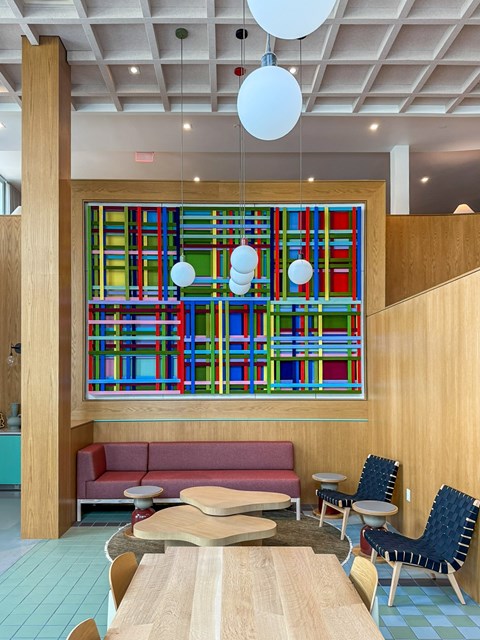 A colorful abstract painting hangs on a wall above a red couch and a wooden table.