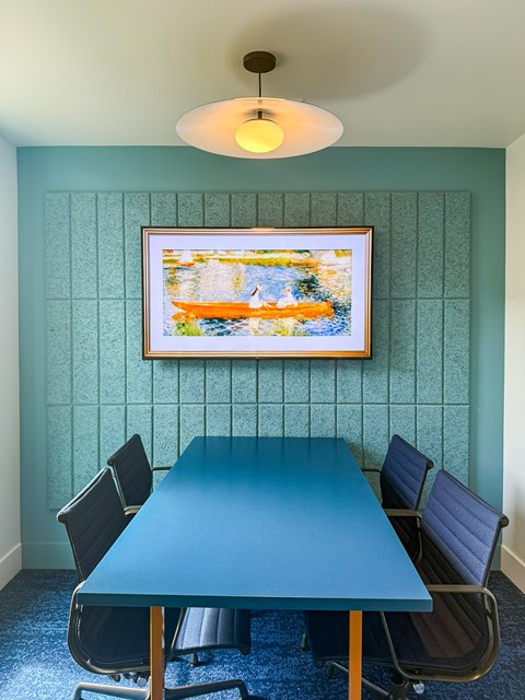 A blue table with four chairs and a painting on the wall.