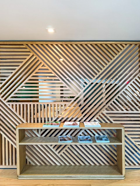 A wooden shelf with books on it in front of a wall with a striped pattern.