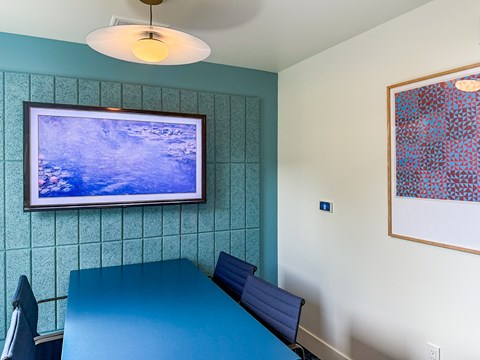 A blue table with a bench and a painting on the wall.