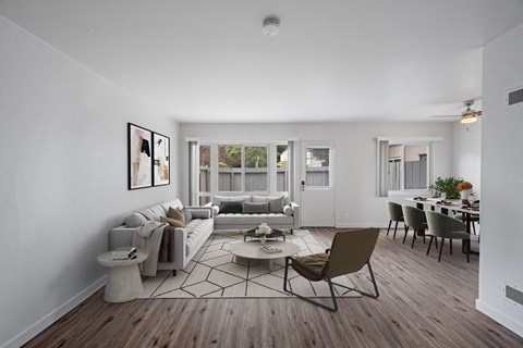 A living room with a grey sofa, a coffee table, and a dining table with chairs.