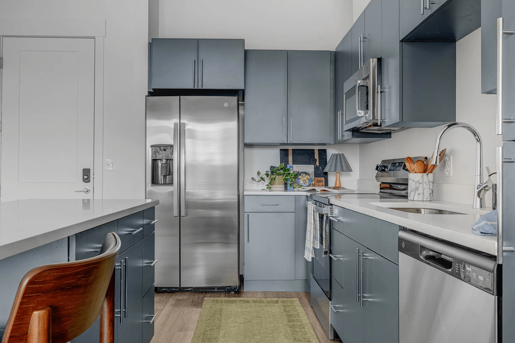 A kitchen with a refrigerator, oven, and sink.