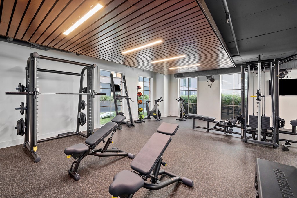 A gym with a variety of equipment including a squat rack, bench, and weights.