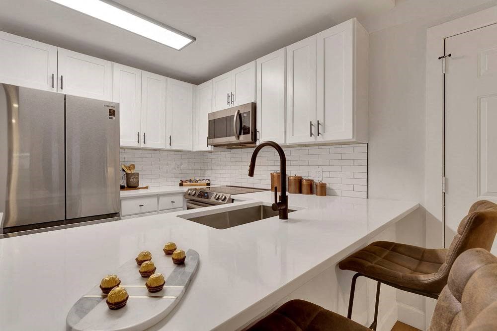 A kitchen with a white countertop and brown chairs.