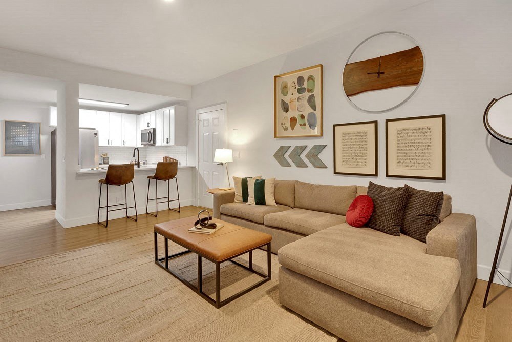 A living room with a couch, chairs, and pictures on the wall.