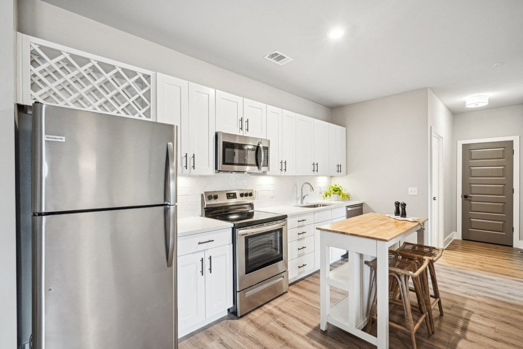 a white kitchen with stainless steel appliances and a wooden table