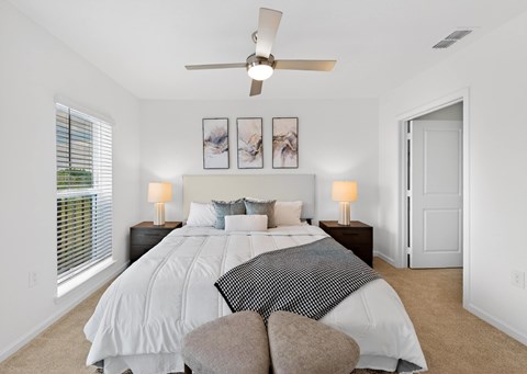 A bedroom with a large bed and a ceiling fan.