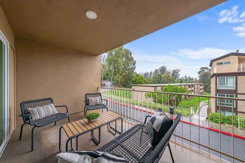 a balcony with two wicker chairs and a table with a plant on it