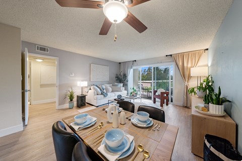 a living room with a dining room table and a ceiling fan