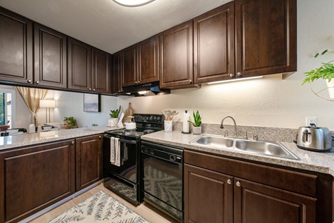 full kitchen with black appliances and brown cabinets at the preserve at greatstone