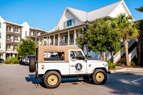 A white jeep with a tan top is parked in front of a building.
