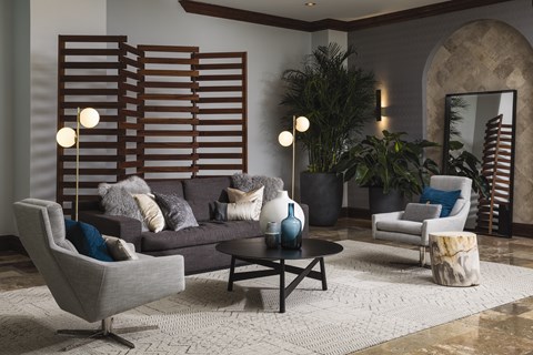 A living room with a grey couch, a black coffee table, and a large mirror.