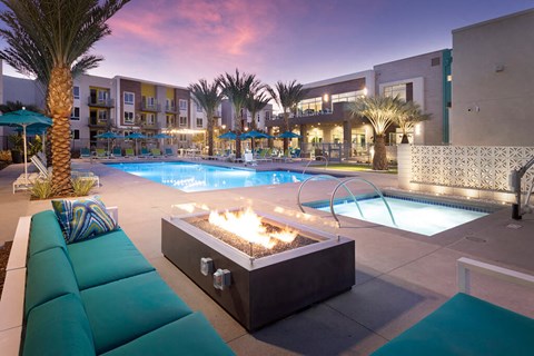 Outdoor courtyard at Rivue apartments in Chula Vista San Diego with a fireplace, couch, and the pool with lounge chairs.