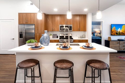 a kitchen with three stools in front of a counter top