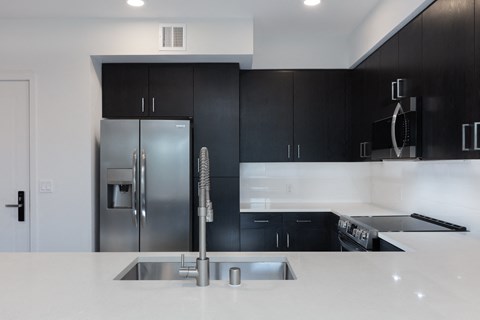a white kitchen with black cabinets and a stainless steel refrigerator