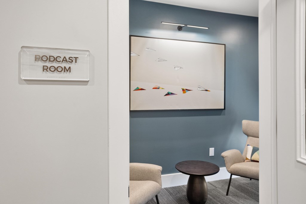 A room with a table and chairs and a sign that says Podcast Room.