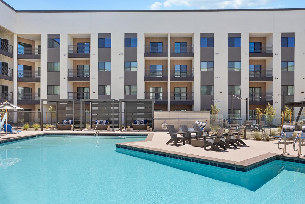 A large swimming pool in front of a multi-story apartment building.