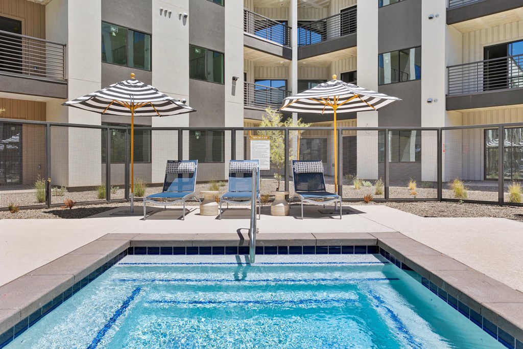 A swimming pool with a blue tiled edge and a striped umbrella.