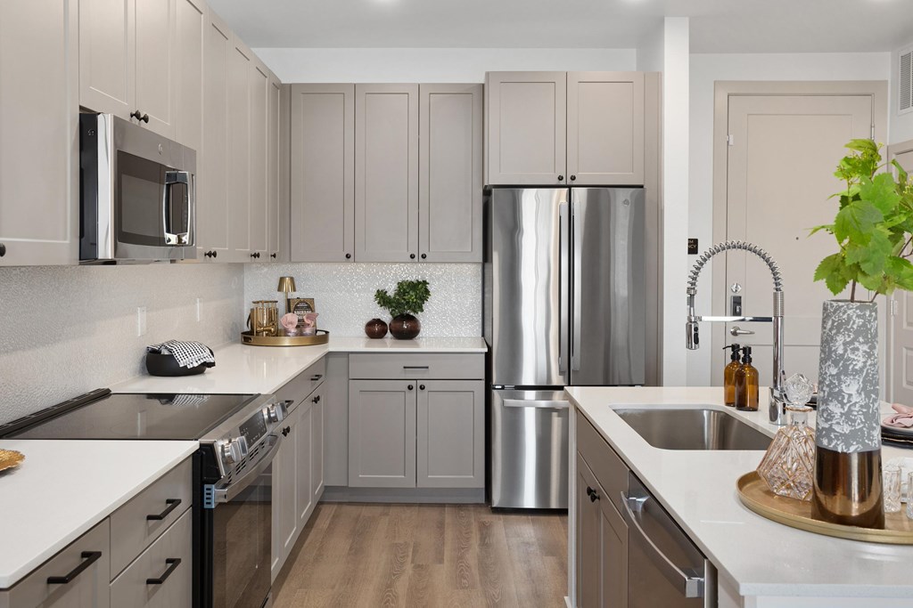 A modern kitchen with a stainless steel refrigerator and wooden floors.