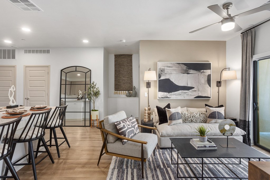 A modern living room with a dining area and a ceiling fan.