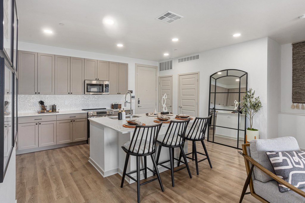 A kitchen with a white countertop and a dining table with four chairs.