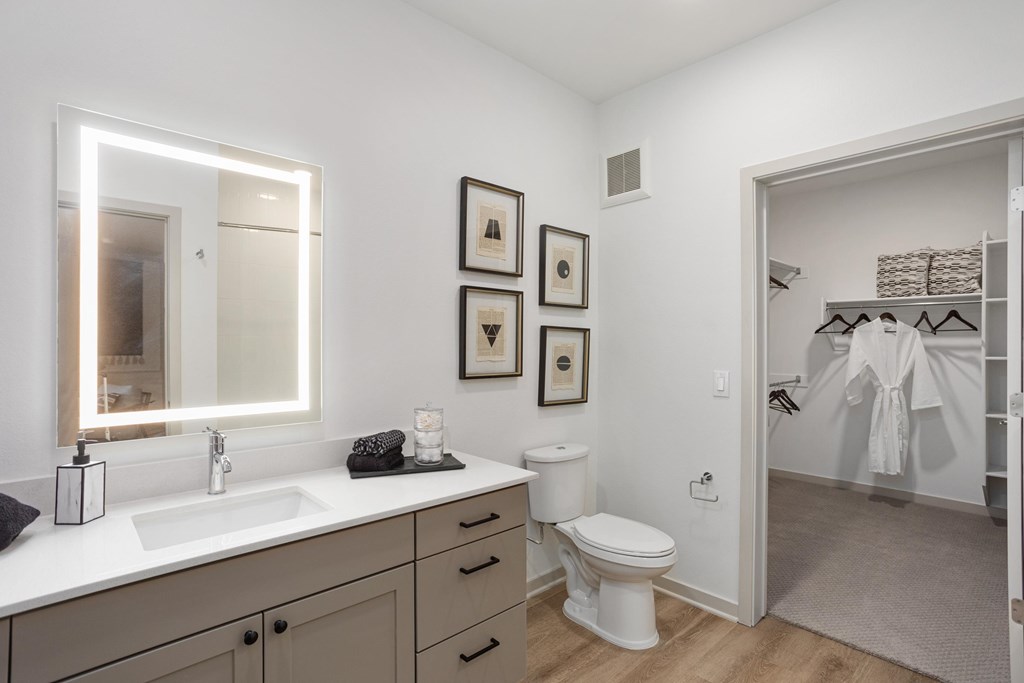 A bathroom with a white toilet, sink, and mirror.