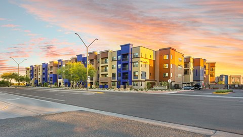 A row of modern apartment buildings are lined up along a street.