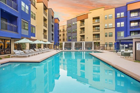 A large swimming pool in front of apartment buildings.