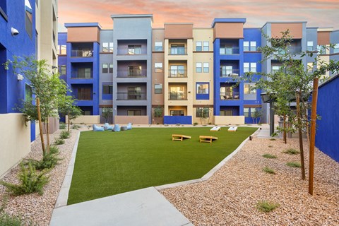 A modern apartment complex with a grassy courtyard in the foreground.